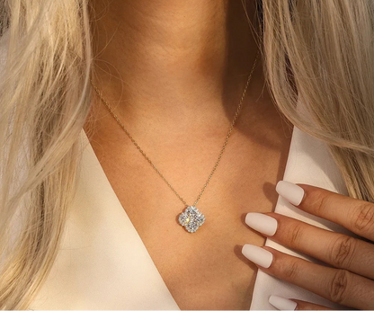 Model mit blonden Haaren trägt eine goldfarbene Halskette aus 14K vergoldetem Silber mit einem kleeblattförmigen Zirkonia-Anhänger, der auf dem Dekolleté liegt.