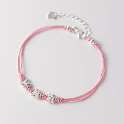 Rosa Ausführung des feinen Textilarmbands mit drei filigranen Schmetterlingen aus 925er Silber auf hellem Untergrund.