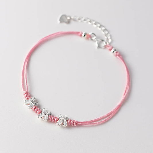 Rosa Ausführung des feinen Textilarmbands mit drei filigranen Schmetterlingen aus 925er Silber auf hellem Untergrund.