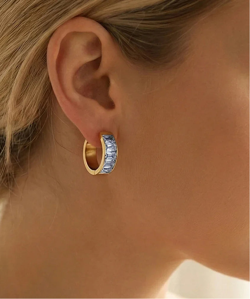 Model trägt goldene Edelstahl-Ohrringe mit 18K Goldbeschichtung und funkelnden Zirkonia-Steinchen am Ohr.