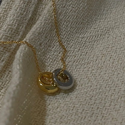 Detailansicht der 18K vergoldeten Messingkette mit zwei kreisförmigen Anhängern auf weißem Stoffuntergrund.