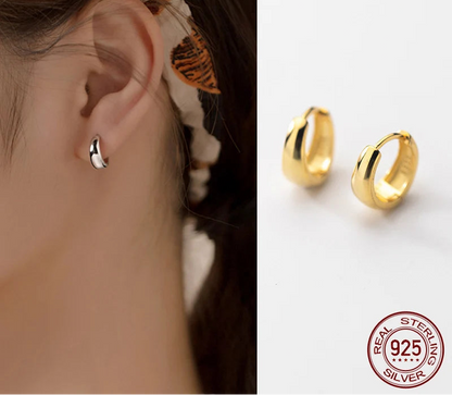 Zwei breite, glänzende Creolen (Hoops) aus 18K Gold vergoldetem 925er Sterling Silber, drapiert auf grauem Satin.