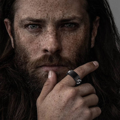 Porträtaufnahme eines Mannes mit einem schwarzen oder silberfarbenen Edelstahl-Gliederring am Finger.