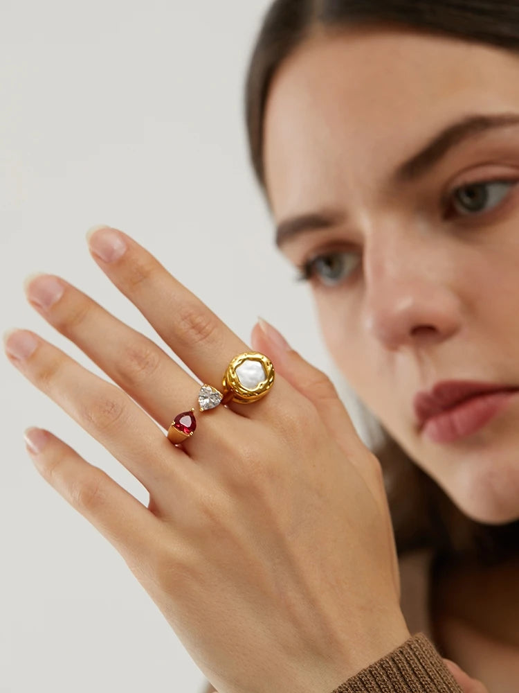 Ansicht des 18K vergoldeten Cocktailrings am Finger eines Models, zeigt die klassische Perle und rote Zirkonia