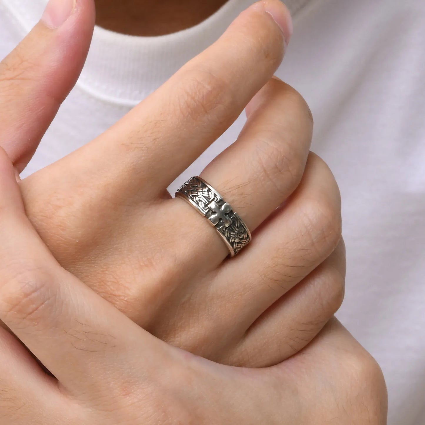 Ein Mann trägt den silberfarbenen Edelstahl-Ring mit Kreuz-Muster am Ringfinger (hellere Hautfarbe).