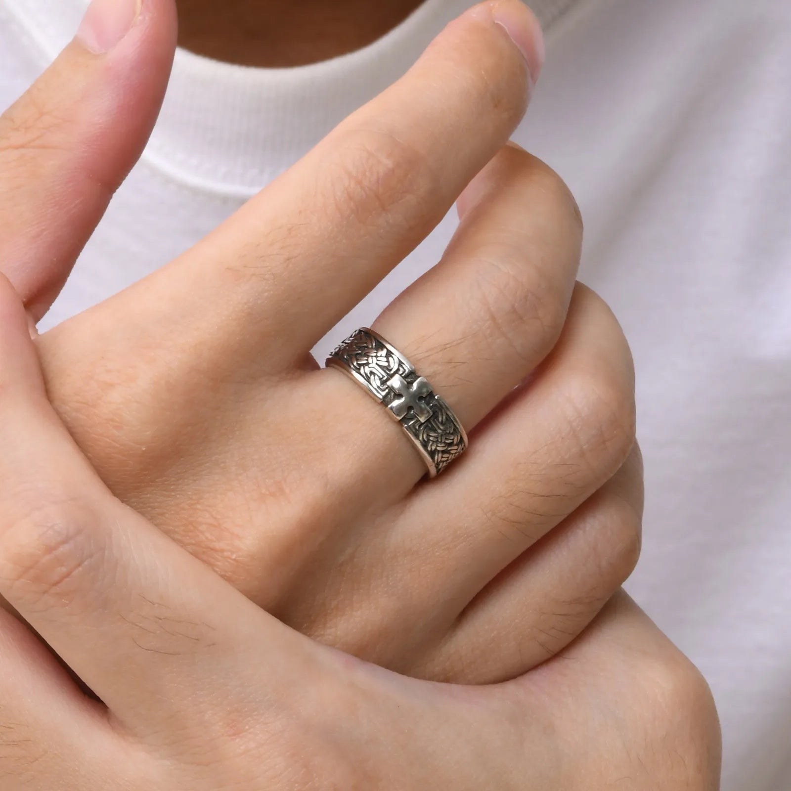 Ein Mann trägt den silberfarbenen Edelstahl-Ring mit Kreuz-Muster am Ringfinger (hellere Hautfarbe).