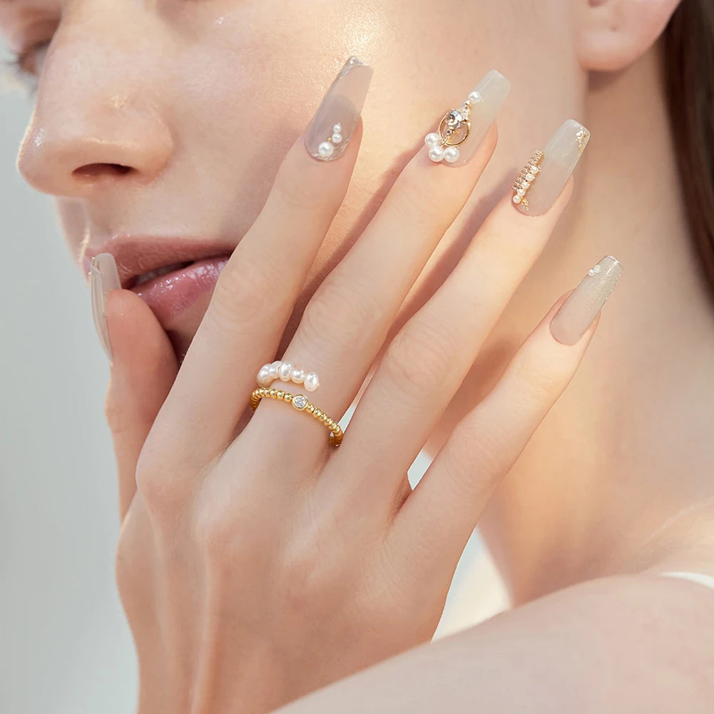 Model trägt eleganten, spiralenförmigen Ring mit kleinen Süßwasserperlen und 14K Gold vergoldetem Band am Finger.