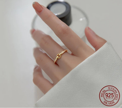 Filigraner Ring aus 18K vergoldetem 925er Sterling Silber mit einem eleganten Knoten-Design und funkelndem Zirkonia-Besatz, getragen an der Hand einer Frau.