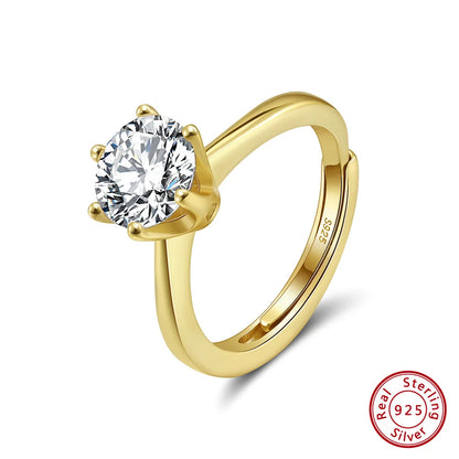 Freigestellter, verstellbarer Ring aus 14K vergoldetem 925er Sterling Silber, der einen großen, runden Zirkonia-Stein in Krappenfassung präsentiert. Das 'Real 925 Sterling Silver' Echtheitssiegel ist unten rechts erkennbar.