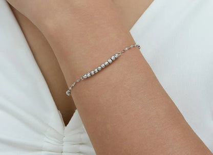 Ein filigranes, silbernes Armband aus 925er Sterling Silber am Handgelenk eines Models, das ein helles Outfit trägt.