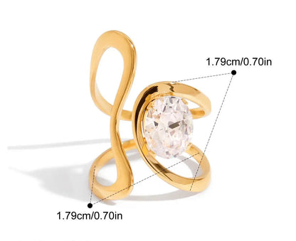  Grafische Darstellung eines goldenen Rings mit 18K PVD-Vergoldung. Er hat eine spiralförmige Form, die sich um den Finger wickelt und ist mit einem großen, klaren Zirkonia Stein besetzt. Die Maße sind ebenfalls angegeben mit einem Innendurchmesser von 1,8 cm und einer Breite von 1,8 cm.