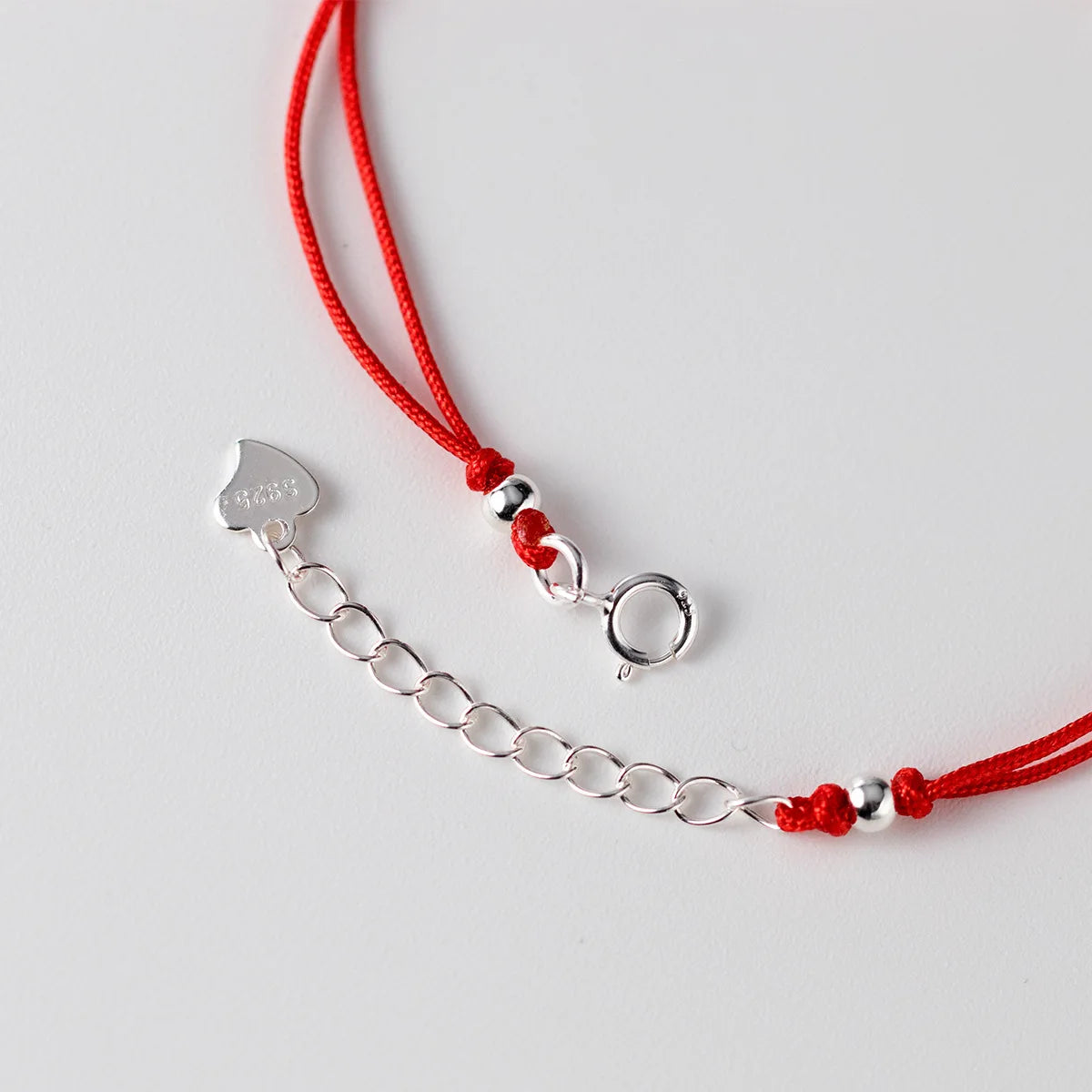 Detailaufnahme des verstellbaren Federring-Verschlusses aus 925er Silber mit Verlängerungskette am roten Kordelarmband.