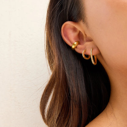 Kleine goldene Creolen getragen an Ohr einer Frau | PVD 18K vergoldete Edelstahl-Ohrringe | minimalistischer Ohrschmuck