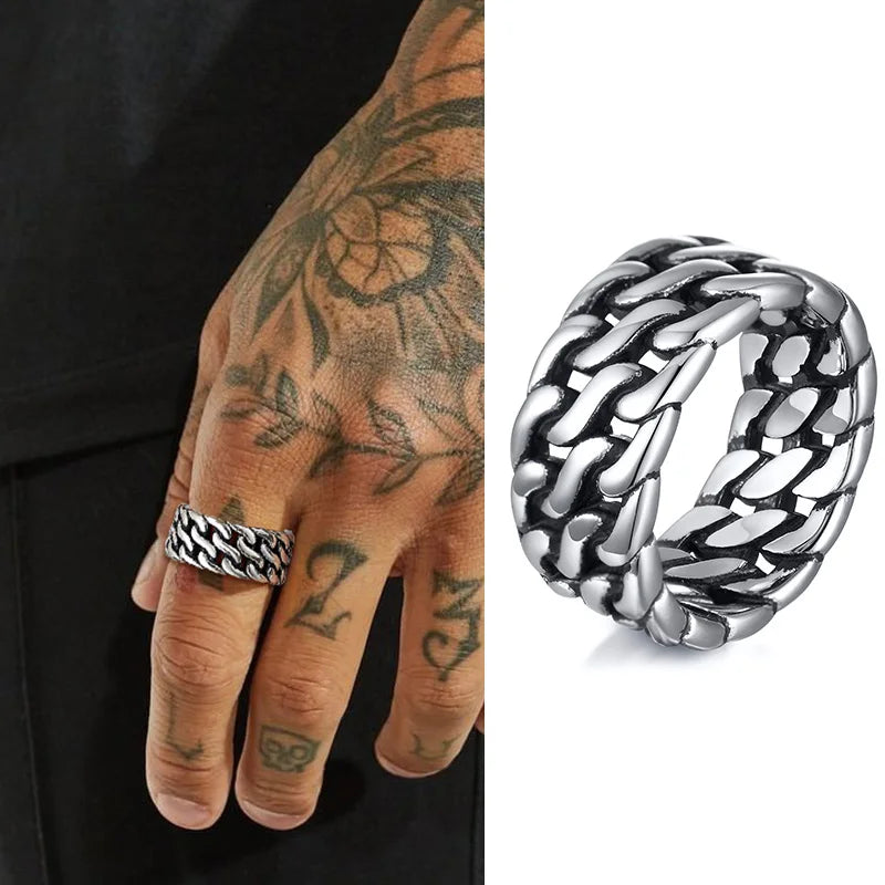 Nahaufnahme eines Mannes mit Tattoos an der Hand, der einen breiten, silberfarbenen Edelstahl-Ring im Panzerketten-Design (Cuban Link) trägt.