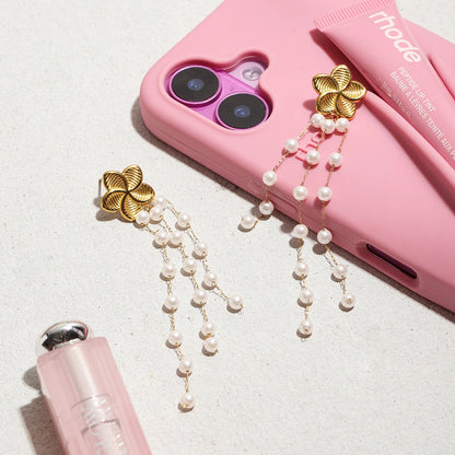 Ein Paar Blumen-Ohrhänger aus 18K vergoldetem Edelstahl mit Acrylperlen, auf einer pinken Handyhülle liegend.