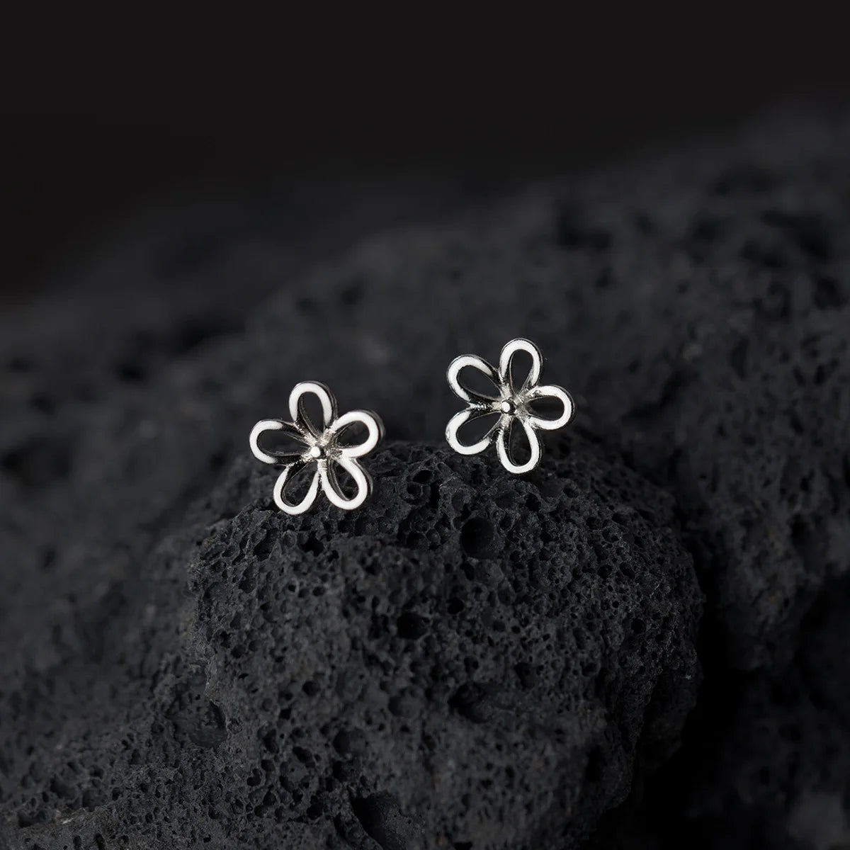 Detailansicht der Rück- und Vorderseite der filigranen Silber-Blumen-Ohrstecker auf dunklem Untergrund.