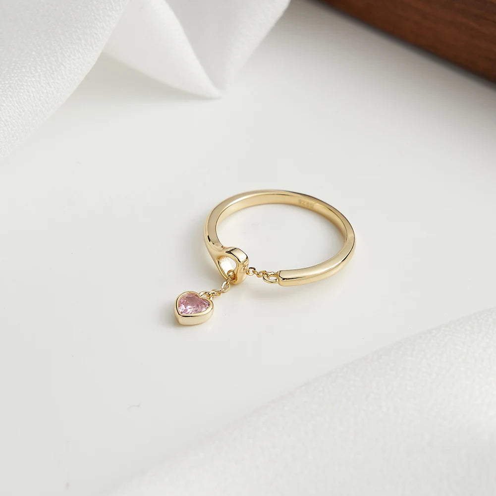 Ring aus 18K Gold mit rosa Zirkonia-Herzanhänger auf weißem Hintergrund.