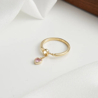Ring aus 18K Gold mit rosa Zirkonia-Herzanhänger auf weißem Hintergrund.
