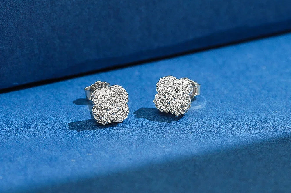 Freisteller eines Paares silberfarbener Kleeblatt-Ohrstecker aus reinem 925er Sterling Silber, dicht besetzt mit funkelnden Zirkonia-Steinen. Unten rechts ist das 'Real 925 Sterling Silver' Siegel erkennbar.