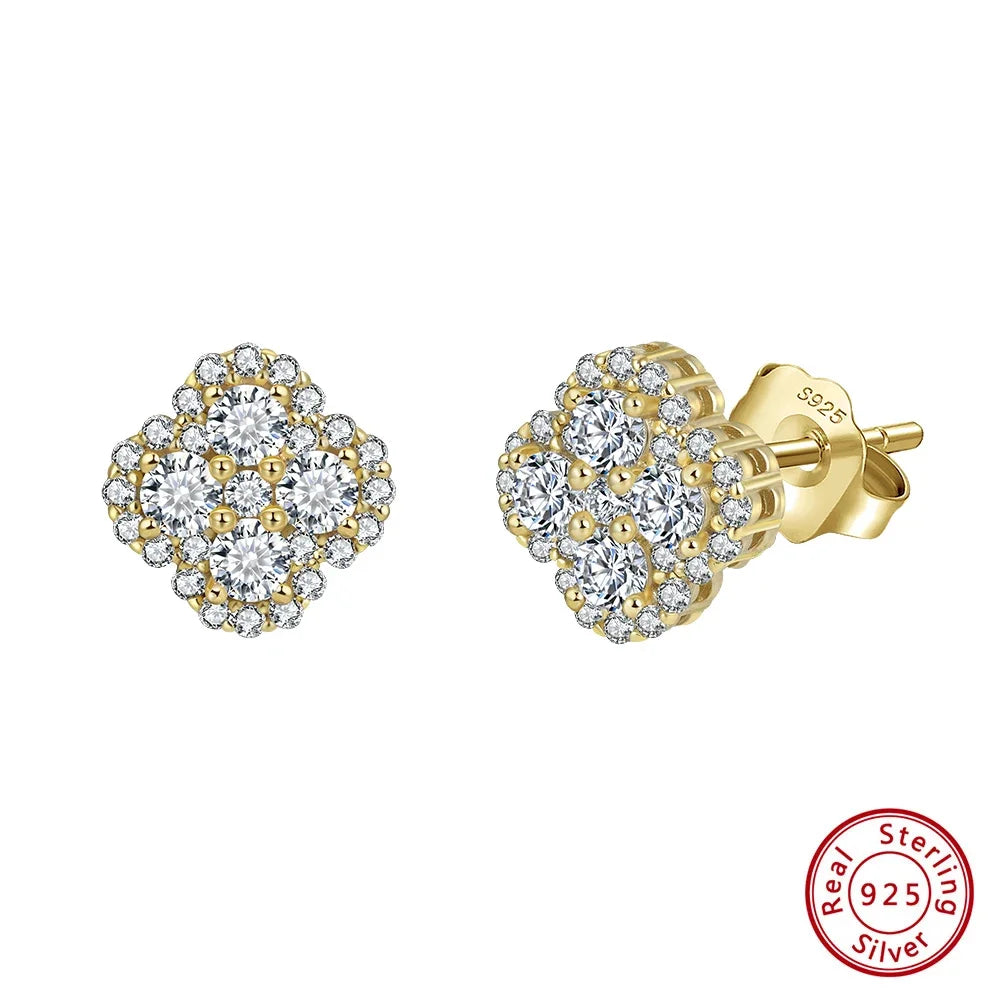 Paar Kleeblatt-Ohrstecker aus 14K vergoldetem 925er Silber, detailreich besetzt mit funkelnden Zirkonia-Steinen, präsentiert auf blauem Untergrund.