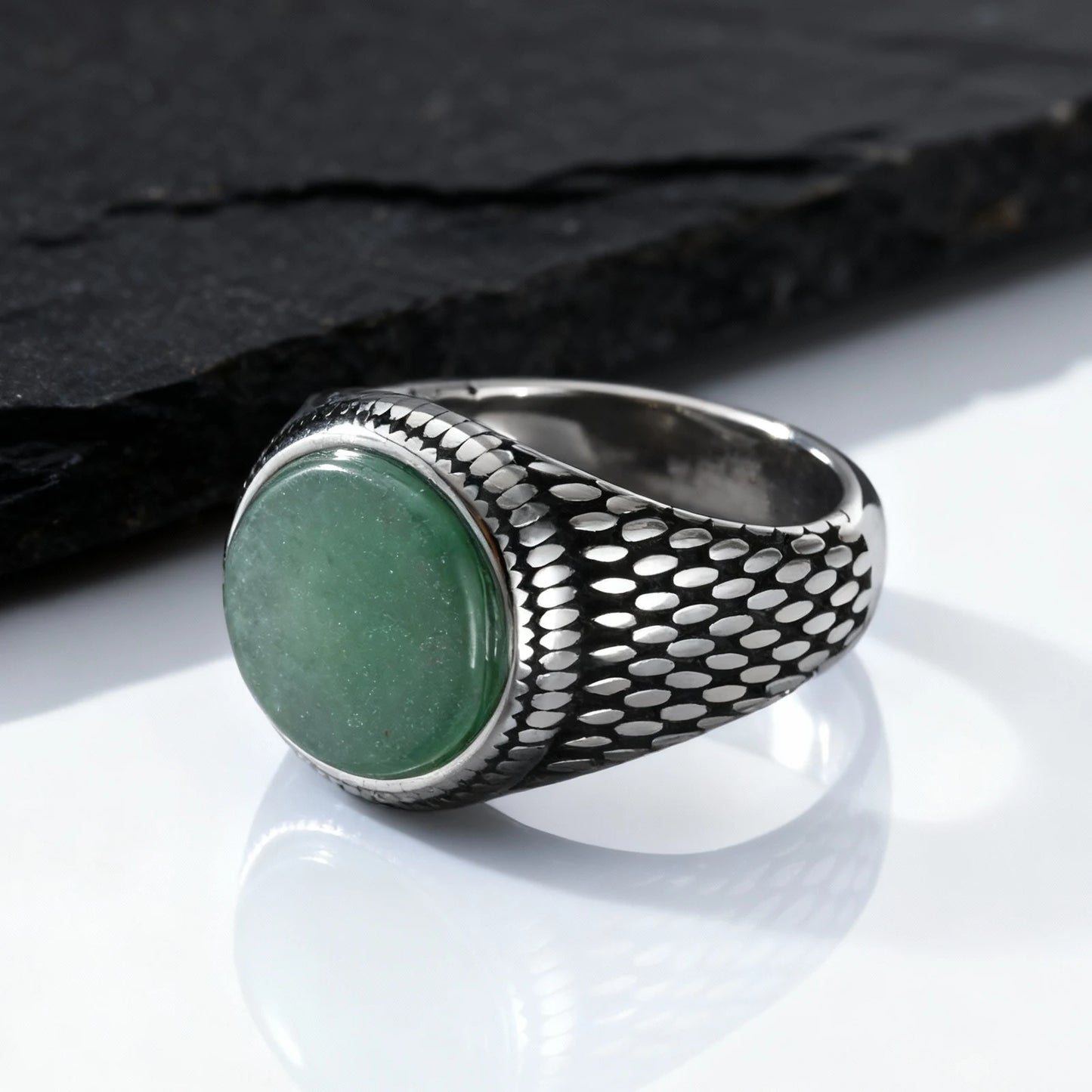 Massiver Herren-Siegelring aus Edelstahl im Vintage-Design mit einem ovalen, grünen Schmuckstein, platziert vor einer dunklen Schieferplatte.
