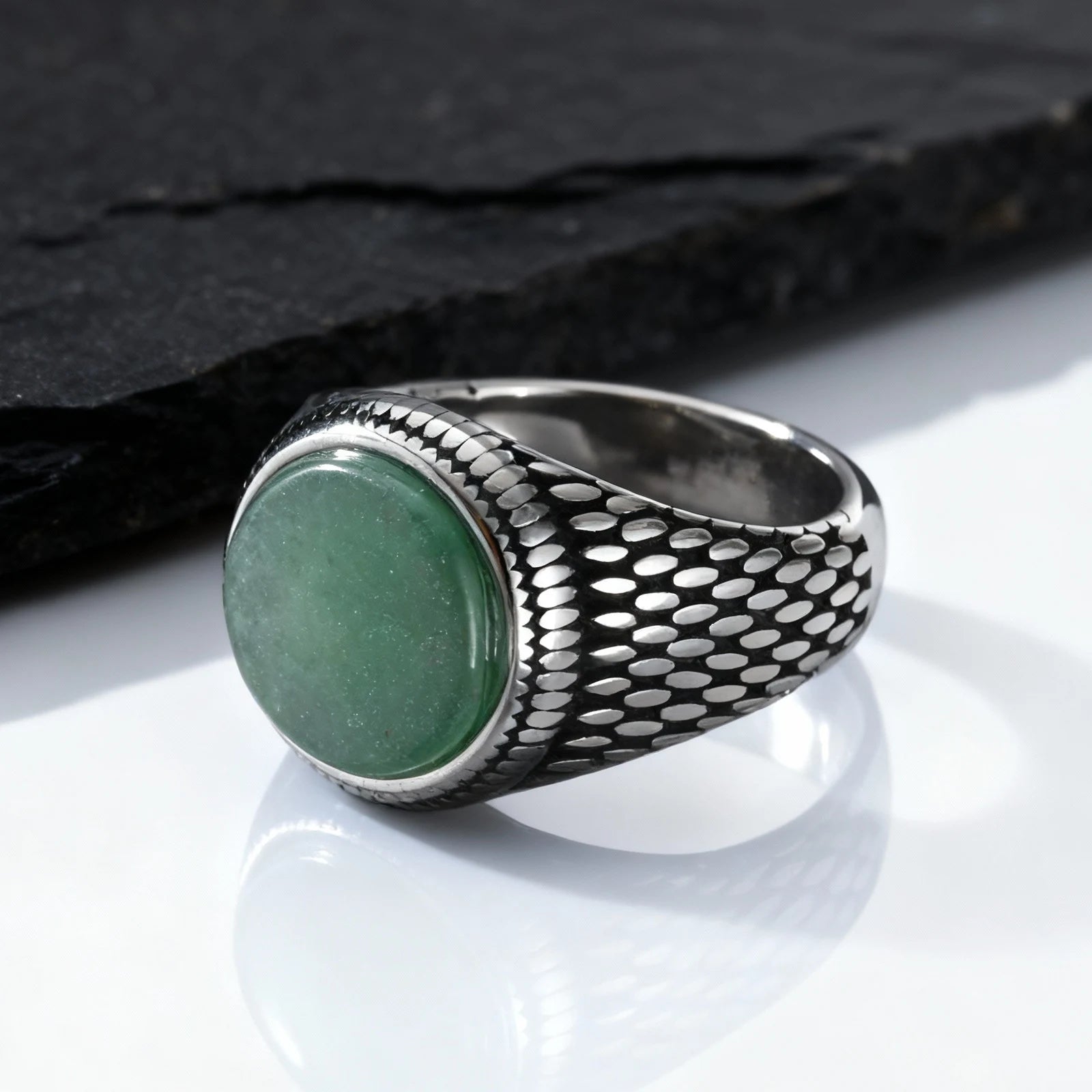Massiver Herren-Siegelring aus Edelstahl im Vintage-Design mit einem ovalen, grünen Schmuckstein, platziert vor einer dunklen Schieferplatte.