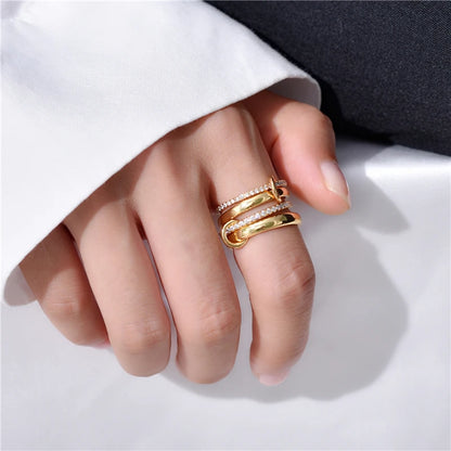 Modernes Schmuck-Styling: Eine Hand trägt den breiten, goldglänzenden Mehrfach-Ring passend zu einem eleganten weißen Business-Outfit.
