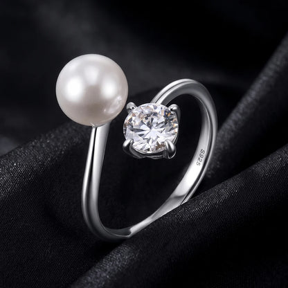 Glänzender offener Perlenring aus 925 Sterling Silber mit rundem Zirkonia und echter Süßwasserperle edel inszeniert auf schwarzem Grund.