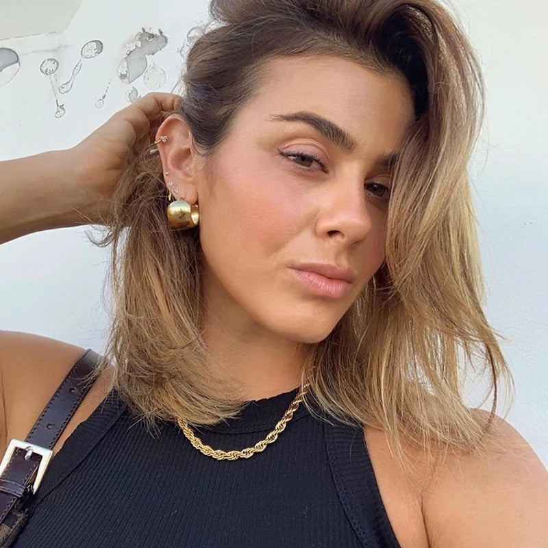 Model trägt glatte, breite, 18K vergoldete Creolen mit passender Goldkette.