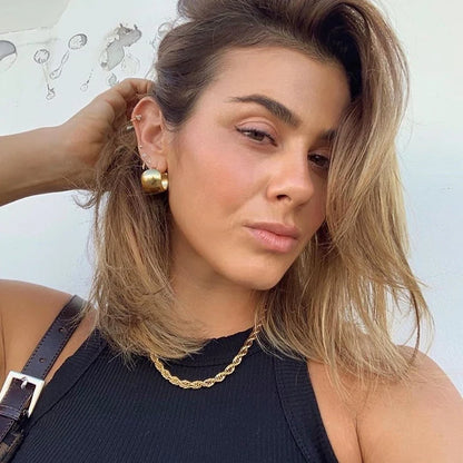 Model trägt glatte, breite, 18K vergoldete Creolen mit passender Goldkette.