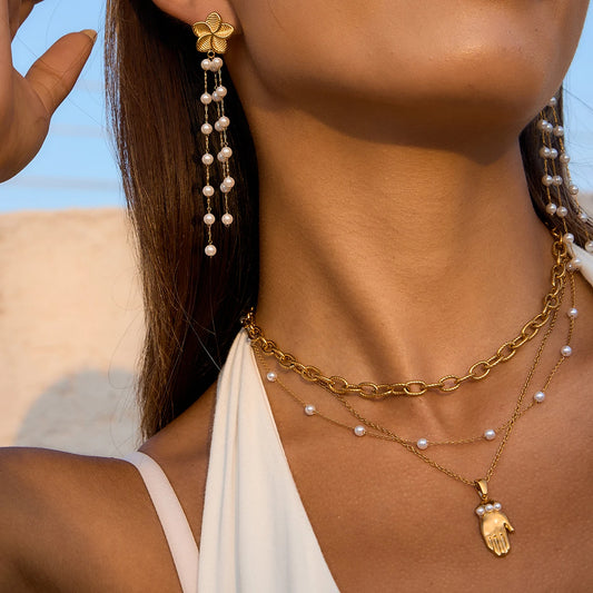 Nahaufnahme von Blumen-Ohrhängern aus 18K vergoldetem Edelstahl mit hängenden Acrylperlen, getragen mit einer passenden goldenen Halskette.