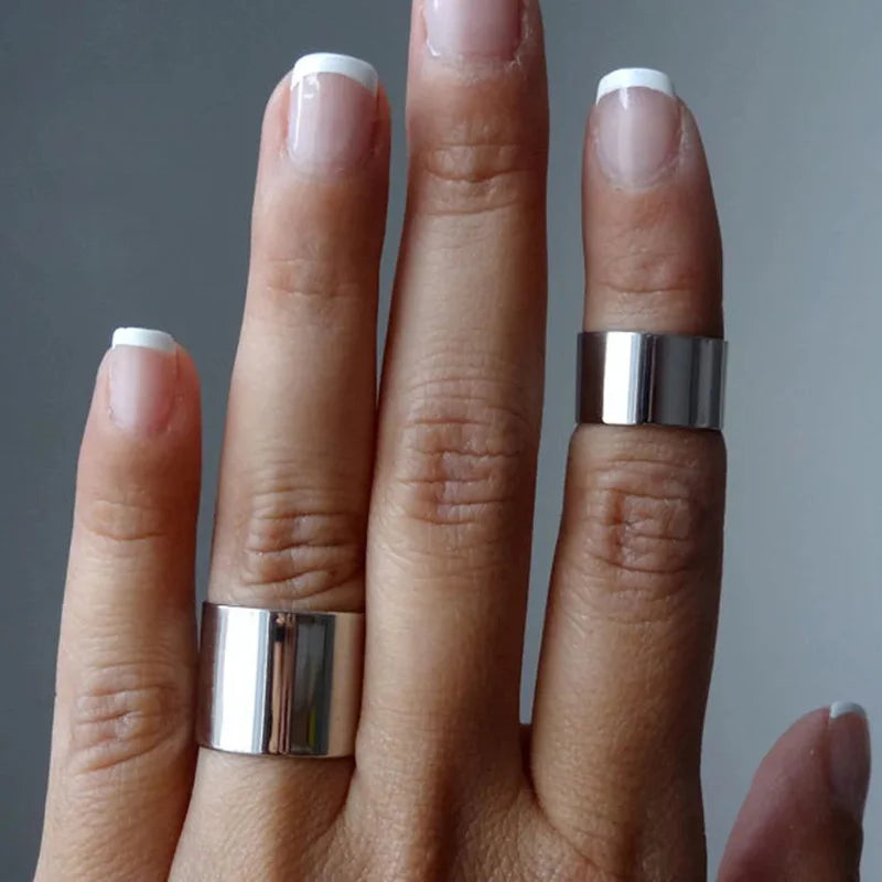 Draufsicht auf eine Hand mit French Nails, die zwei schlichte, offene silberne Bandringe aus Edelstahl in verschiedenen Breiten am Mittel- und Ringfinger trägt.