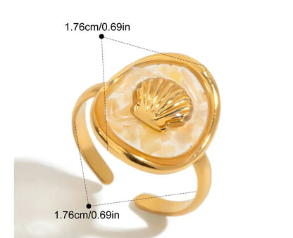 Nahaufnahme eines Rings aus 18K vergoldetem Edelstahl mit einem weißen Muschel-Symbol. Der Ring hat eine Innendurchmesser von 1,76 cm und eine Breite von 1,76 cm.