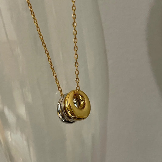 Nahaufnahme der goldenen Halskette mit zwei abgerundeten Anhängern in Bi-Color-Optik (Gold und Silber).