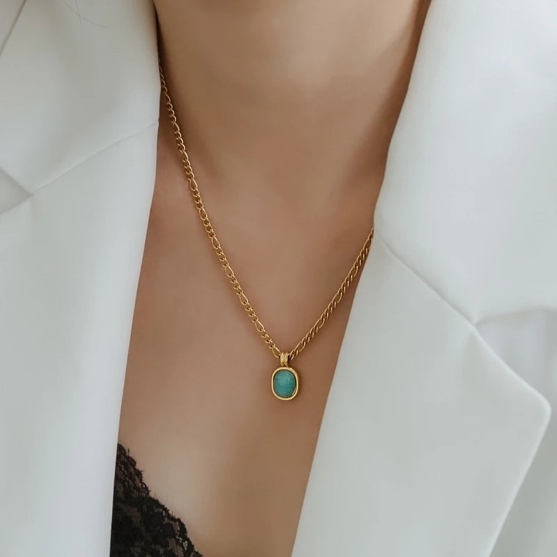 „Elegante Damen-Halskette mit grünem Stein-Anhänger, getragen zu einem weißen Blazer – hochwertiger Titanschmuck.“