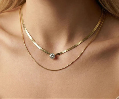 Eine Frau trägt eine zweireihige, vergoldete Edelstahl-Schlangenkette mit einem funkeldem Zirkonia-Stein.