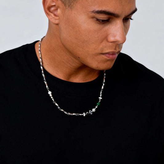 Ein Mann im schwarzen T-Shirt trägt die silberne Design-Edelstahlkette mit grünem und weißem Perlenakzent im lässigen Streetwear-Look.