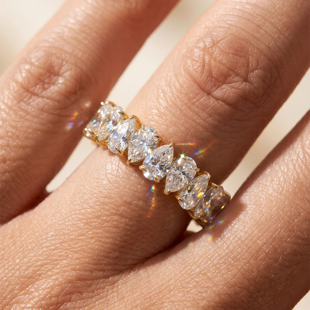 Nahaufnahme am Finger: Brikett- bzw. Eternity-Ring aus 14K vergoldetem 925 Silber, rundum besetzt mit großen Zirkoniasteinen im Birnen-/Tropfenschliff