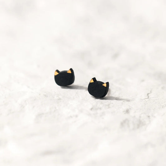 Schwarze Ohrstecker in Katzenkopf-Form aus 925er Silber mit Keramiküberzug und goldenen Ohren auf hellem Untergrund.