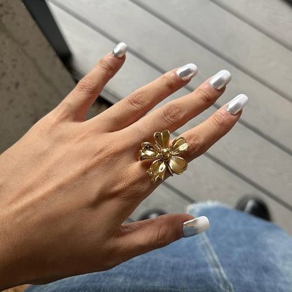 Detaillierte Nahaufnahme des gewellten, vergoldeten Edelstahlrings am Zeigefinger einer Frau, um das moderne Design und die Passform zu zeigen.