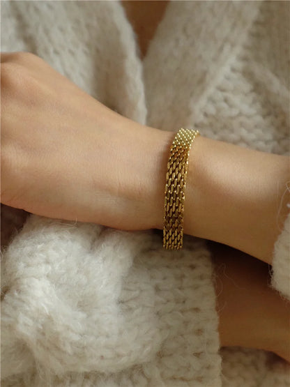 Model trägt glänzendes 18K vergoldetes Fischgräten-Armband, kombiniert mit hellem Strickpullover