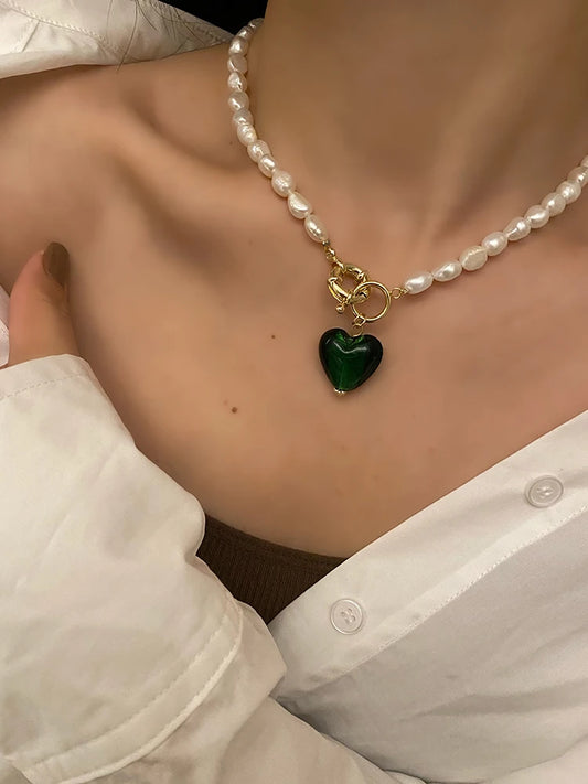 Tragestyling: Naturperlenkette mit 18K vergoldetem Knebelverschluss aus Titan und smaragdgrünem Herz-Anhänger.