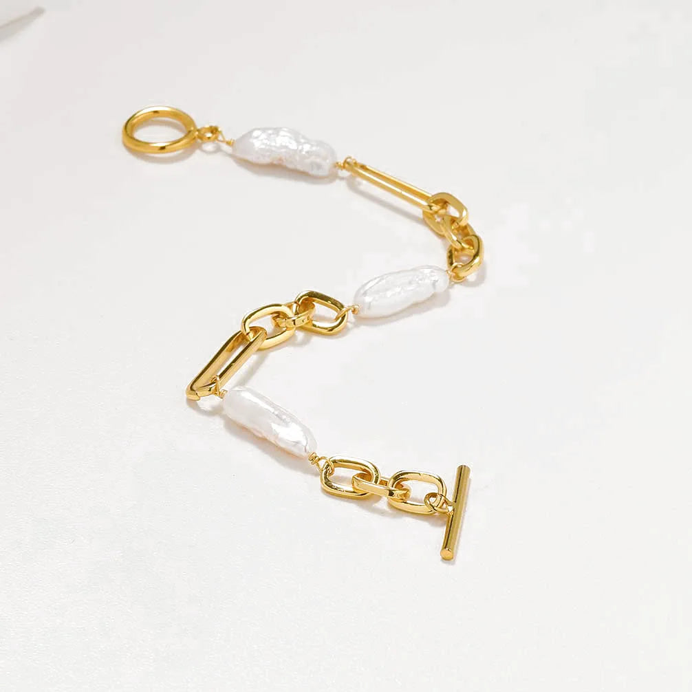 Nahaufnahme eines Gliederarmbands mit abwechselnd polierten Messing-Kettengliedern mit 18 Karat Vergoldung und schimmernden Naturperlen.