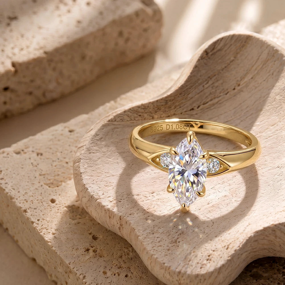 Klassischer Damenring aus 14 Karat vergoldetem Silber mit strahlendem Marquise-Hauptstein auf beiger Deko-Schale