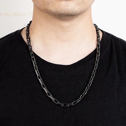 Ein Mann trägt die lange, schwarze Edelstahl-Gliederkette im Vintage-Stil über einem schwarzen T-Shirt. Die Kette liegt locker auf der Brust.
