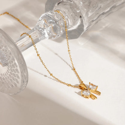 Detailansicht einer goldenen Kügelchenkette mit strahlendem Schleifen-Anhänger an einem verzierten Glas
