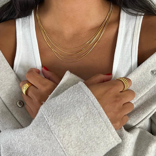 Mehrreihige goldene Edelstahlkette im Layering-Look getragen von einem Model mit weißem Top und Oversized-Jacke