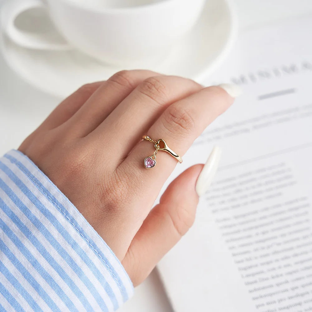 Feiner Ring aus 18K Gold mit rosa Herzanhänger aus Zirkonia, getragen an der Hand.