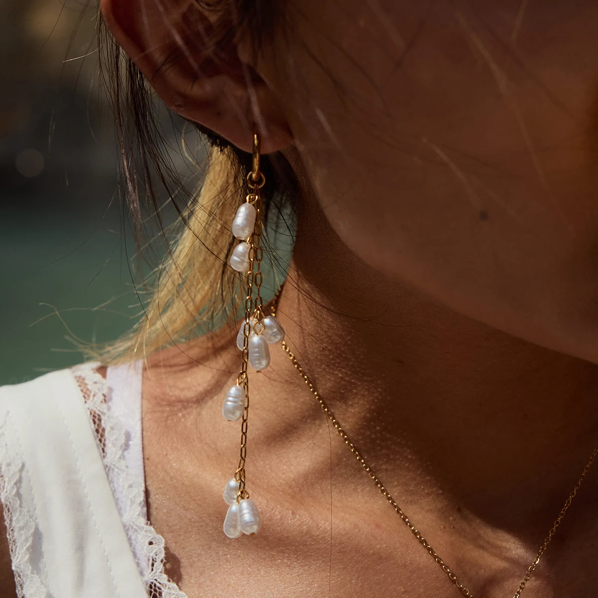 Lange Ohrhänger aus 18K vergoldetem Edelstahl mit hängenden Acrylperlen, am Ohr einer Person getragen.