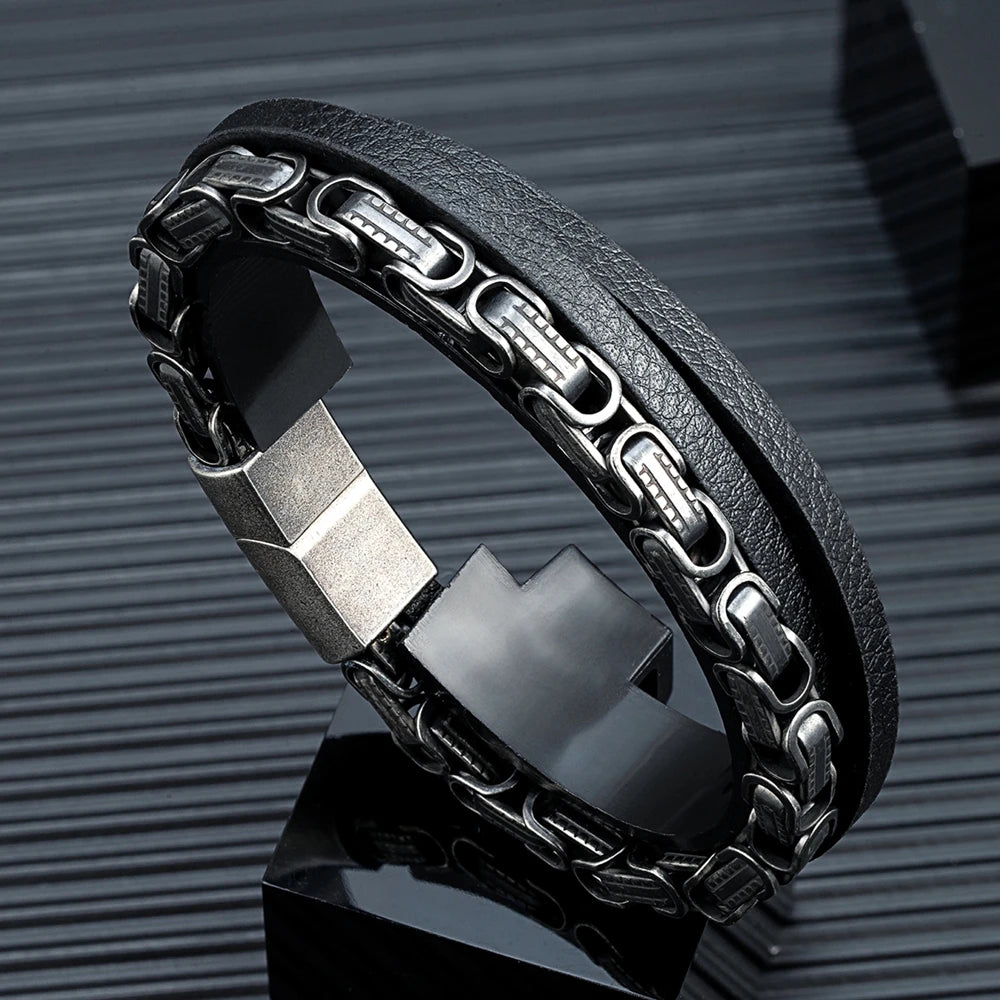 Mehrlagiges Herren-Armband aus schwarzem Mikrofaser-Leder und einer massiven Edelstahl-Königskette im Vintage-Look auf einem dunklen Präsentationswürfel.
